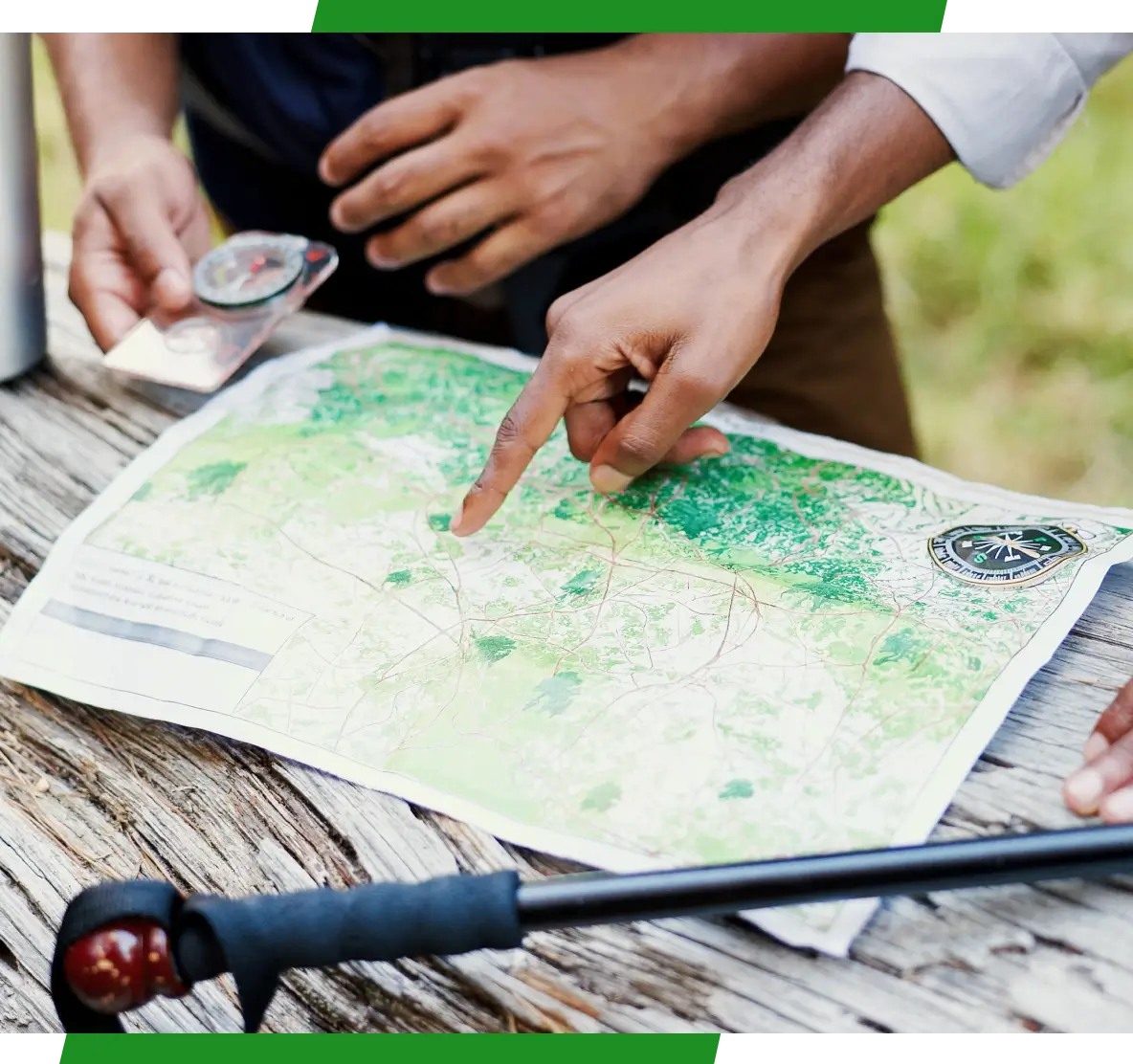 Hands pointing at topographic map and compass